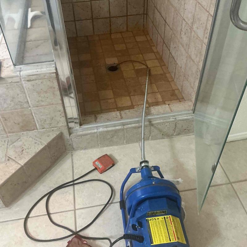 Shower drain line clog clearing with plumbing snake