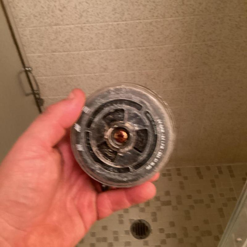 Shower head with mineral buildup held by hand in shower Shower head with mineral buildup held by hand in shower