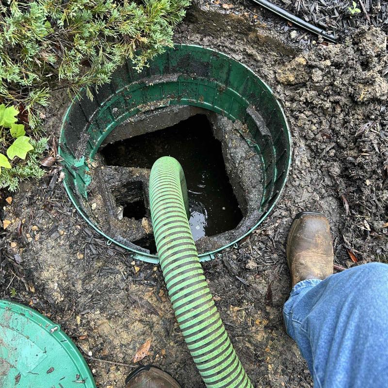 Septic tank riser with green pump hose and boot