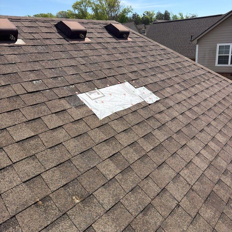 Asphalt shingle roof with temporary patch and hail damage