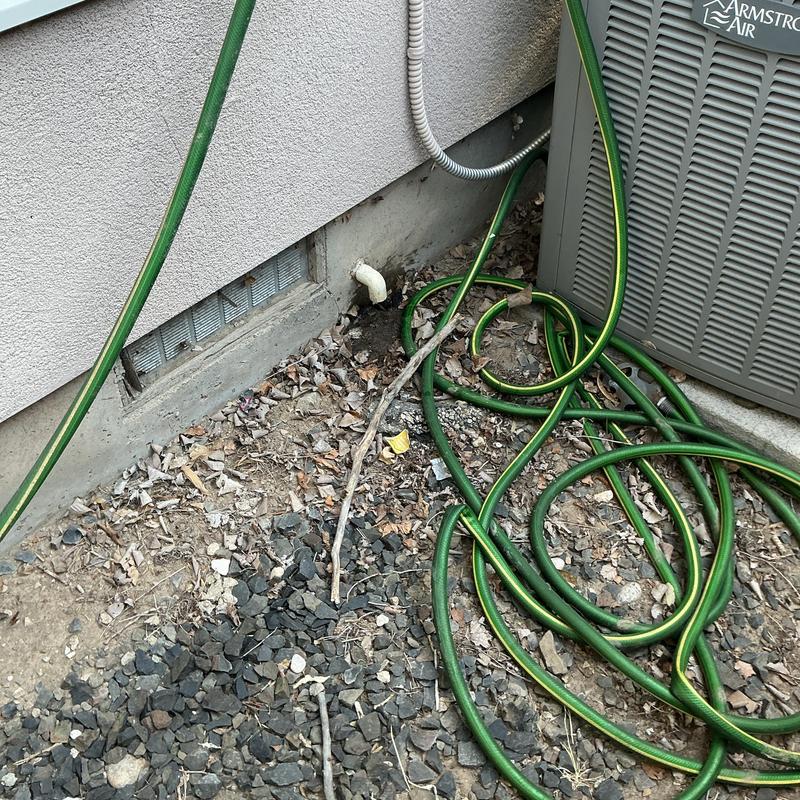 Furnace condensate drain pipe with garden hose and debris