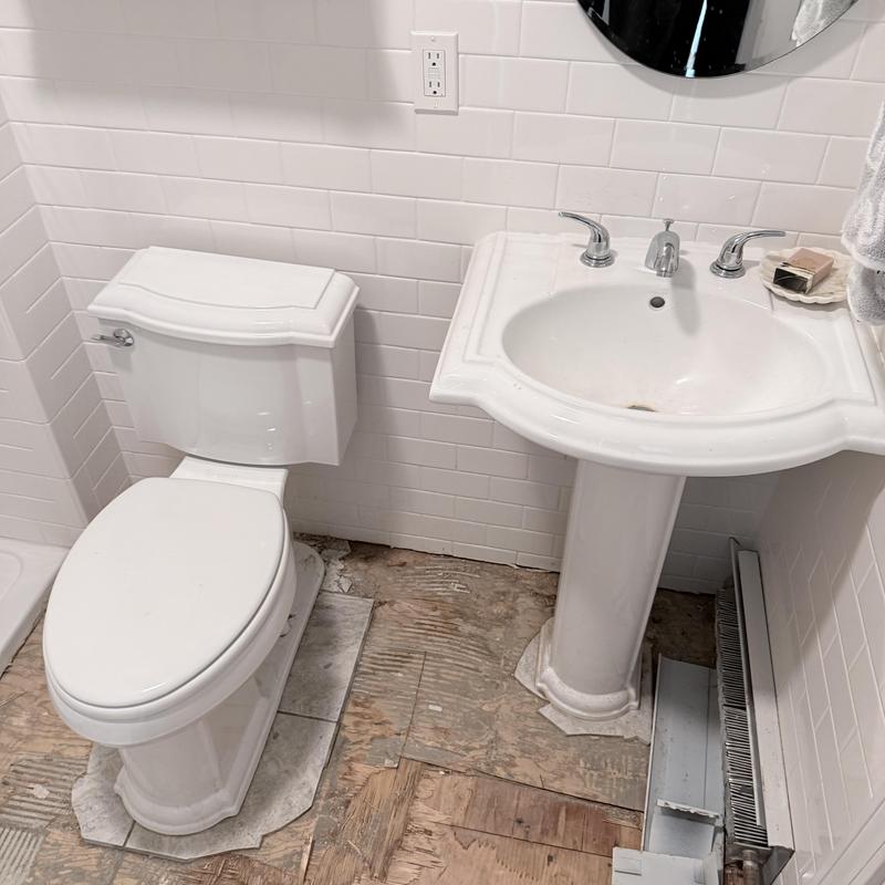 Pedestal vanity and toilet removal with old flooring exposed