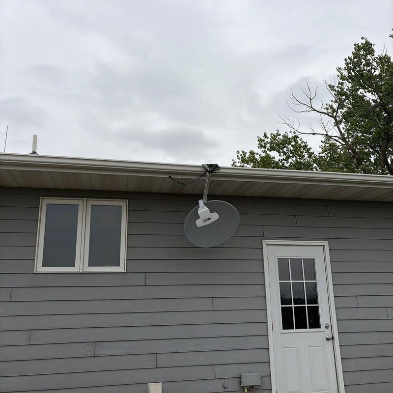 Satellite dish mounted on gray house exterior Satellite dish mounted on gray house exterior