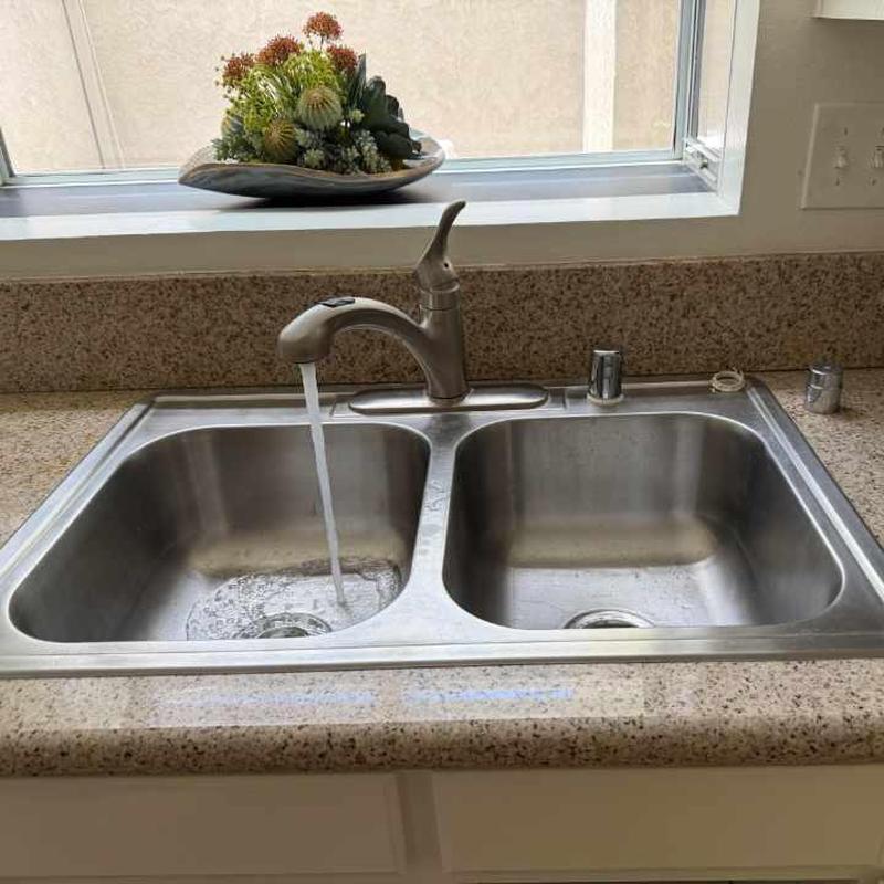 Kitchen sink faucet with running water under window