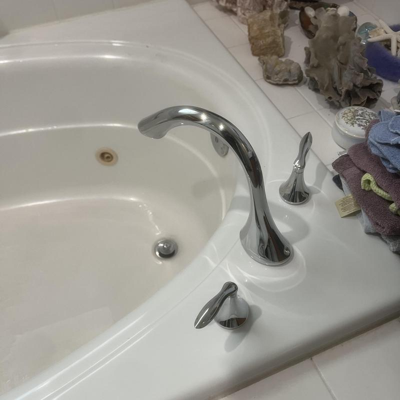 Bathtub faucet and handles installation on white tub edge