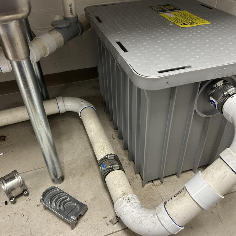 Grease interceptor with connected PVC pipes and clamps