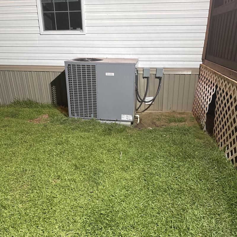 Heat pump unit outside residential home with electrical wiring