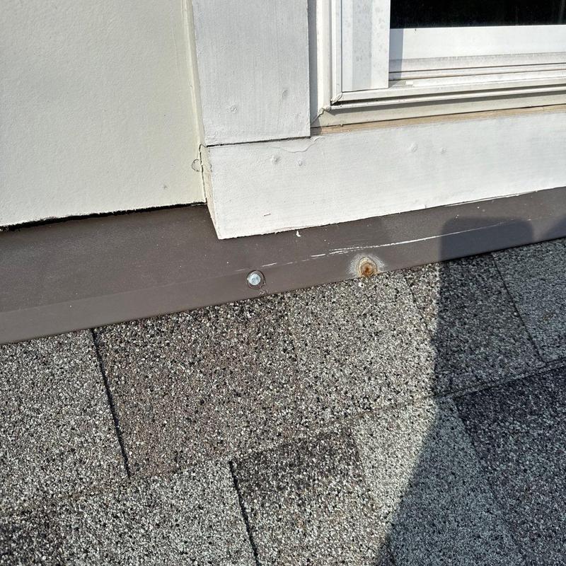 Roof flashing with rusted and new fasteners near trim
