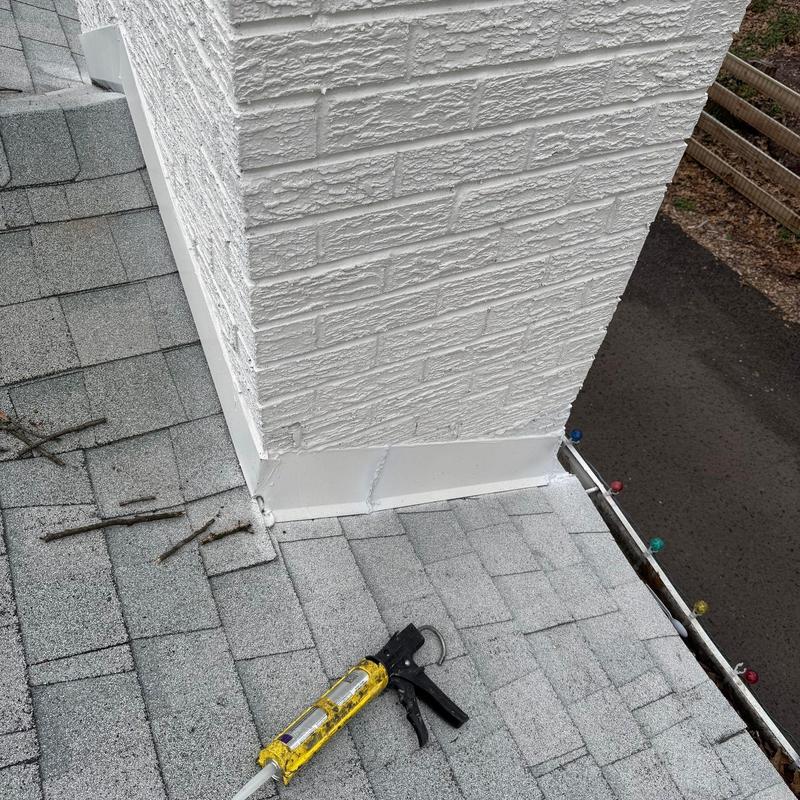Chimney flashing on asphalt shingle roof with sealant gun