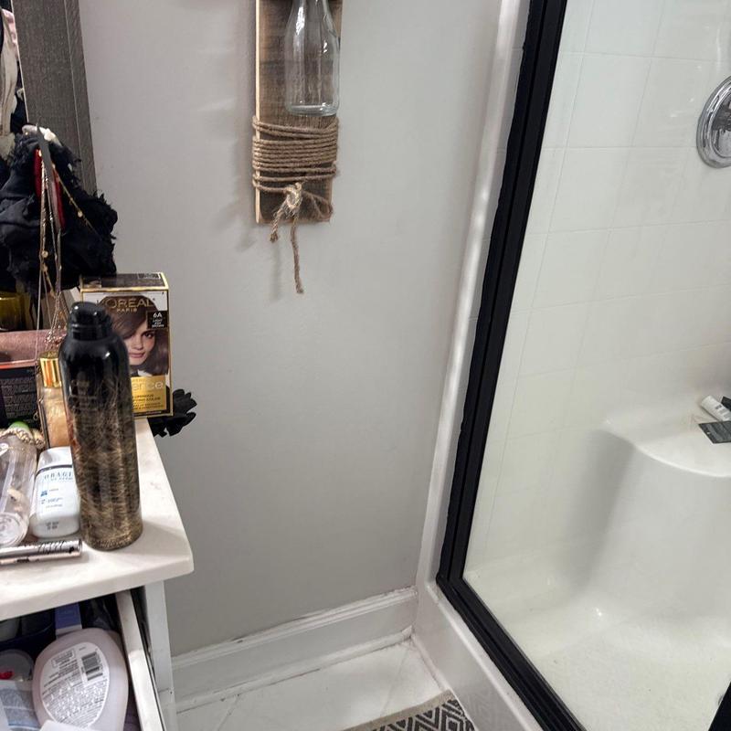 Shower door frame and bathroom wall corner with shelf
