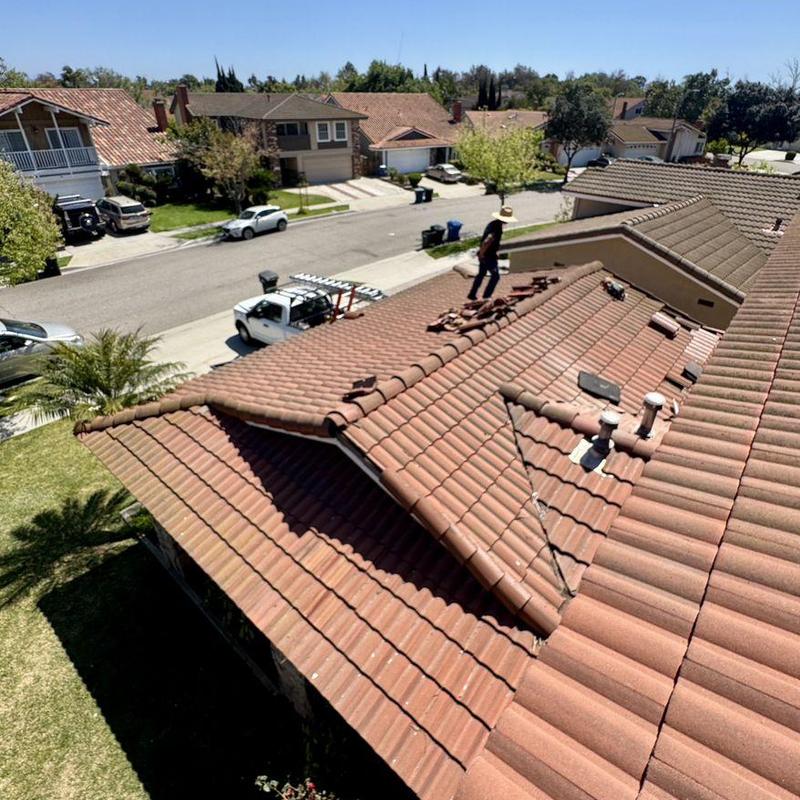 Tile roof with technician inspecting and stacked tiles Tile roof with technician inspecting and stacked tiles