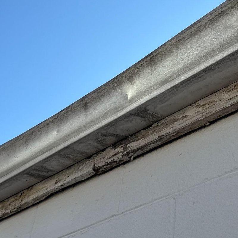 Metal gutter with dented hail damage on commercial roof