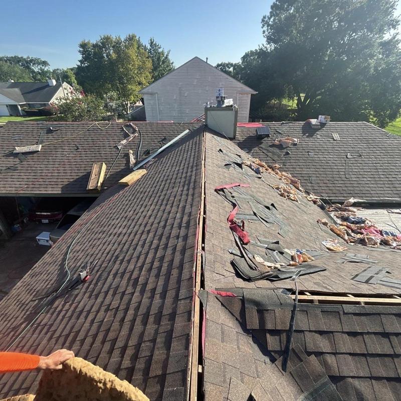 Asphalt shingle roof mid-replacement with torn-off sections