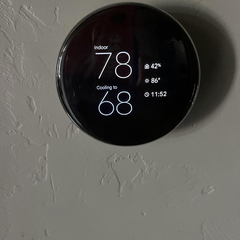 Smart thermostat displaying cooling settings on wall Smart thermostat displaying cooling settings on wall