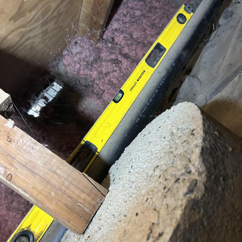 PVC drain pipe with level tool in attic space