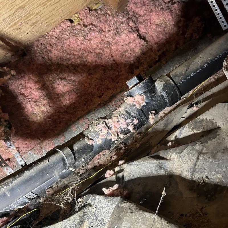 ABS toilet drain pipe with insulation debris in crawl space