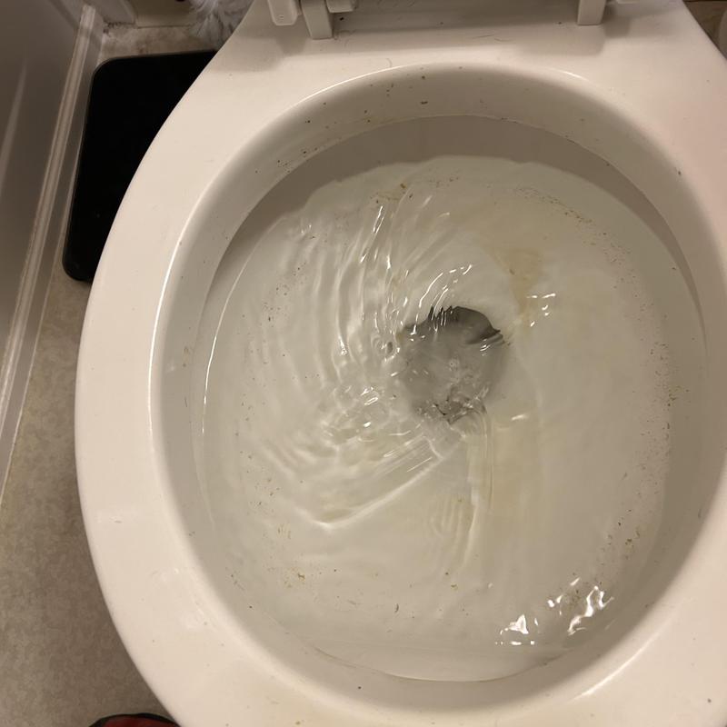 Toilet bowl flushing partially with visible debris