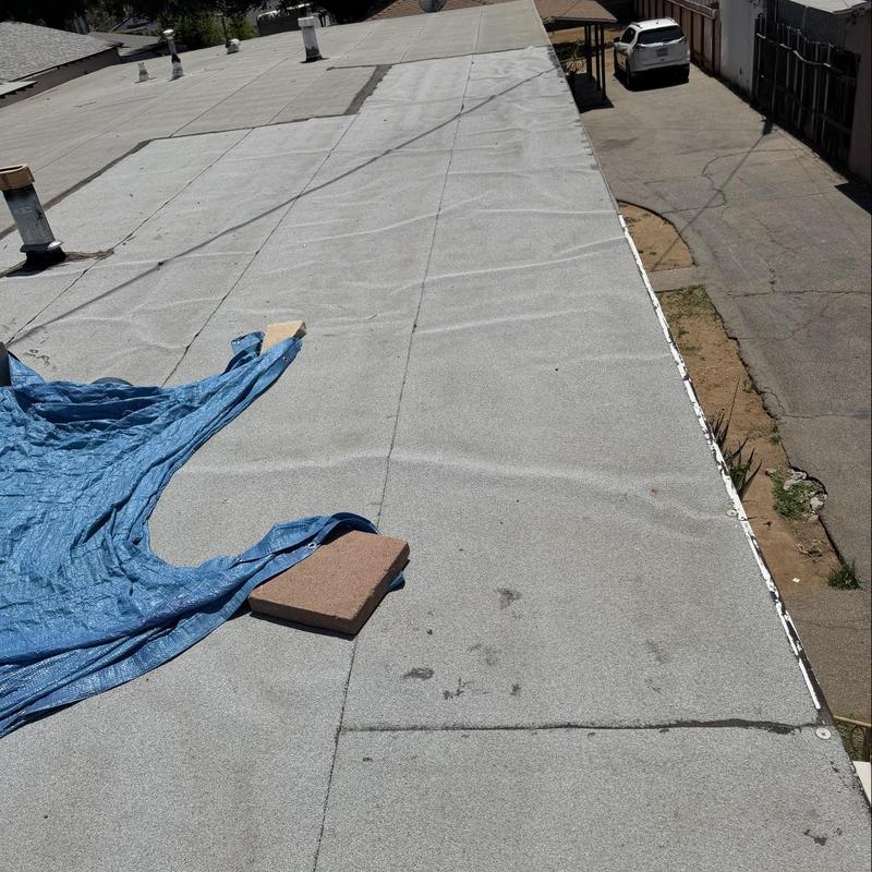 Flat roofing membrane inspection with blue tarp and weights Flat roofing membrane inspection with blue tarp and weights