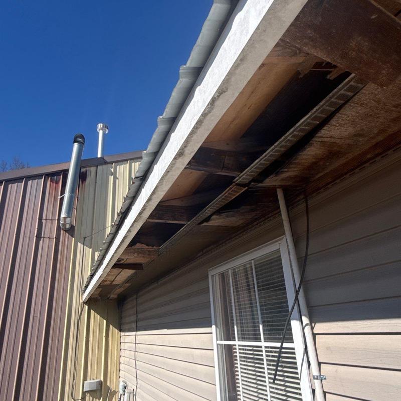 Wooden soffit showing water and hail damage on commercial roof
