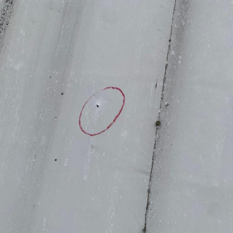 Metal roofing panel with hail damage circled in red