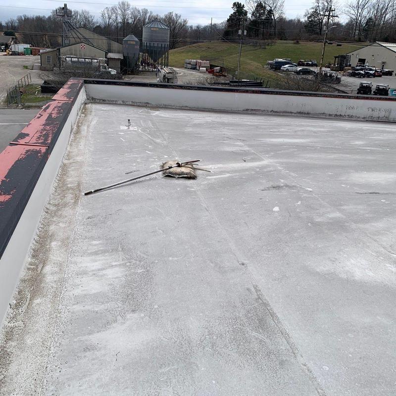 Flat commercial roof surface with hail damage and debris