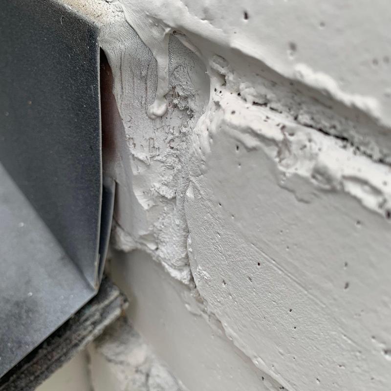 Roof flashing close-up with cracked sealant and paint
