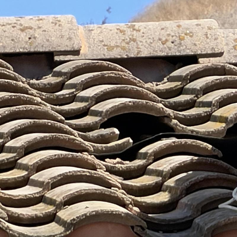 Tile roof with broken and displaced tiles close-up Tile roof with broken and displaced tiles close-up