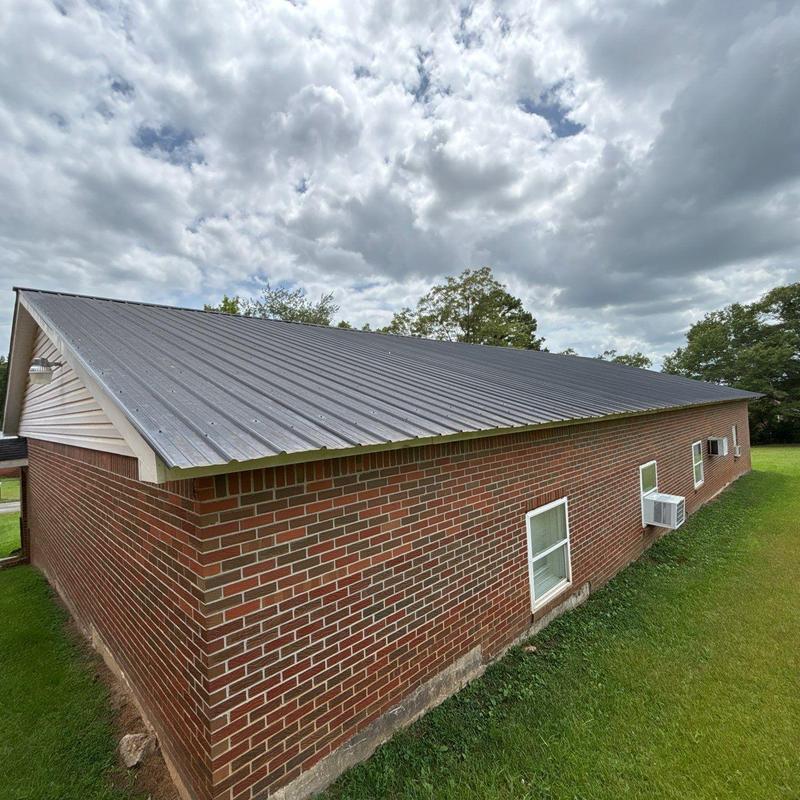 Metal standing seam roof installation on brick building