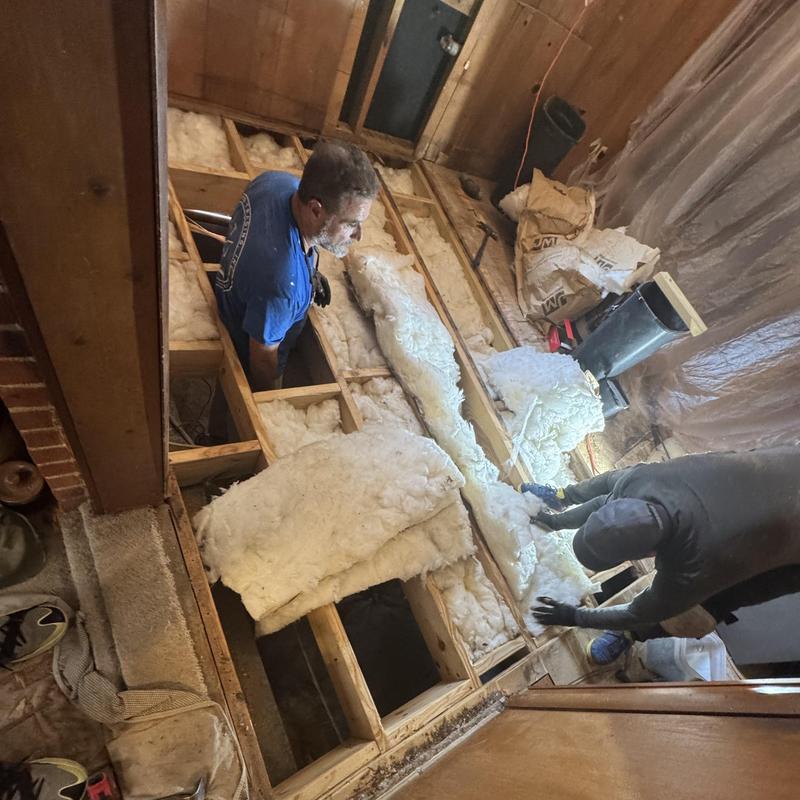 Floor insulation installation with exposed joists and workers Floor insulation installation with exposed joists and workers