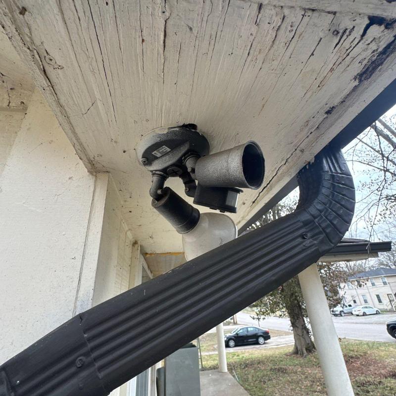 Exterior floodlight fixture under porch ceiling with damaged paint