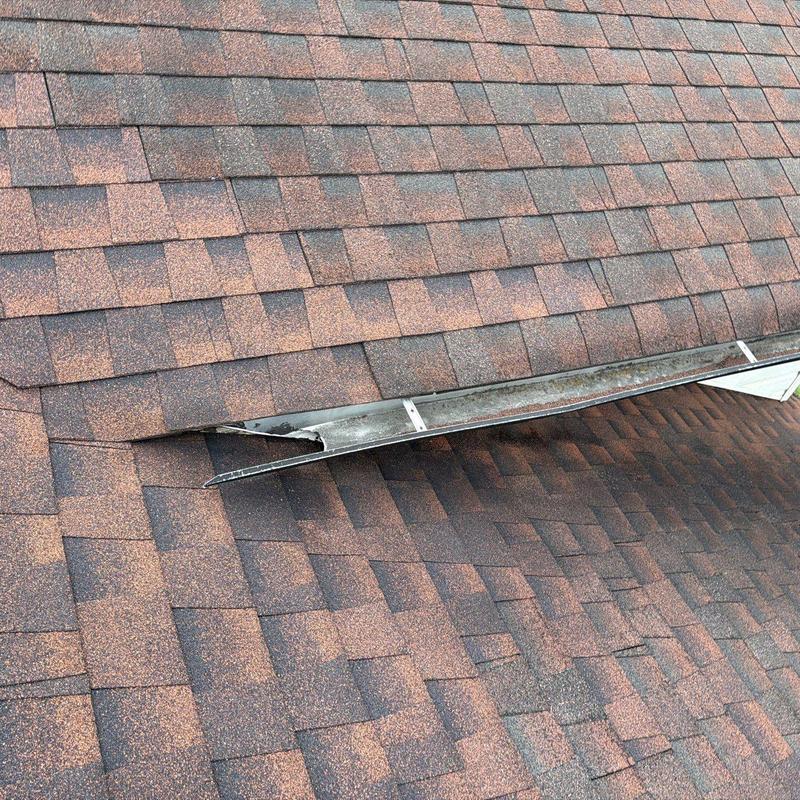 Asphalt shingle roof with damaged metal flashing section