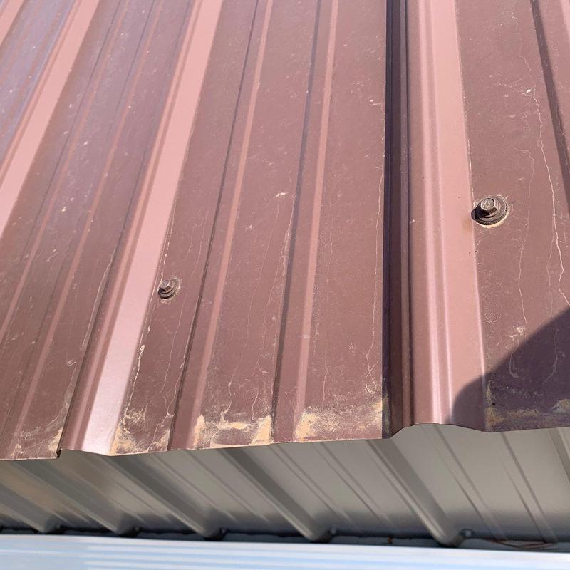 Metal roof panel edges with rust and screws