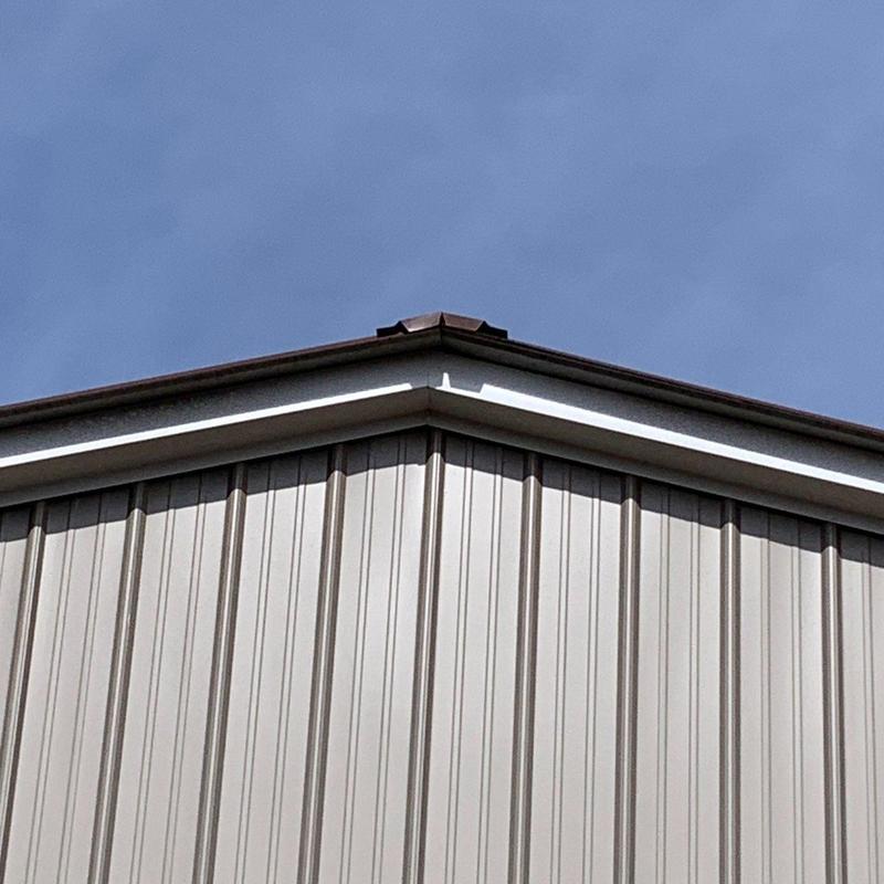 Metal building roof ridge with vent under clear sky