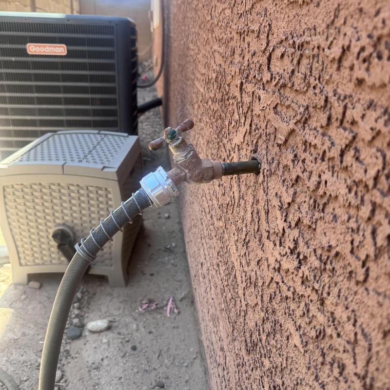 Outdoor hose bib with connected garden hose on stucco wall Outdoor hose bib with connected garden hose on stucco wall