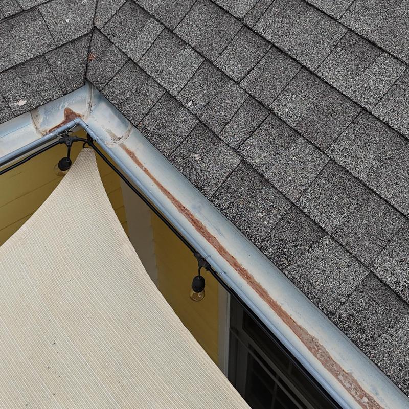 Asphalt shingle roof with rusty metal flashing detail