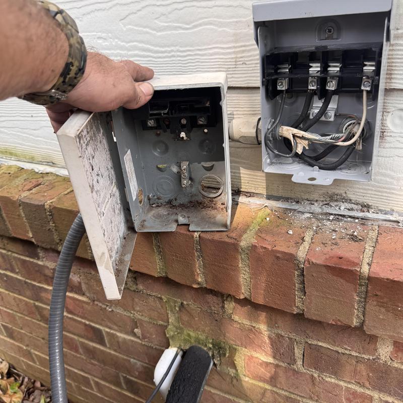 Heat pump disconnect box and electrical wiring on brick wall
