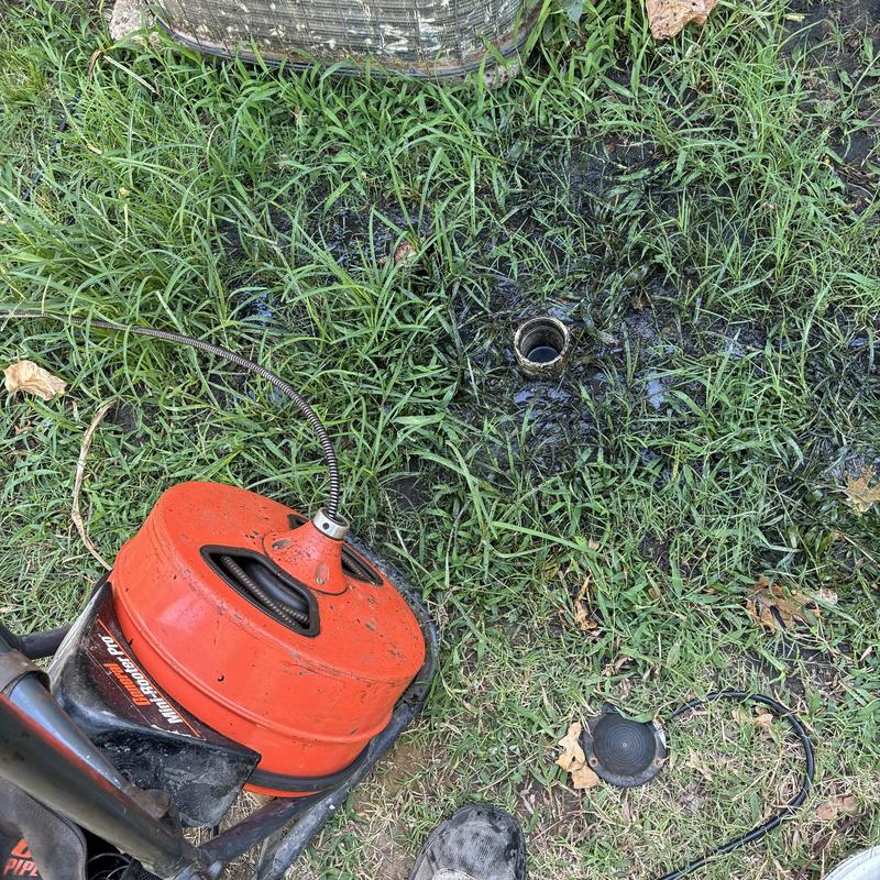 Sewer line drain cleaning machine on muddy grass