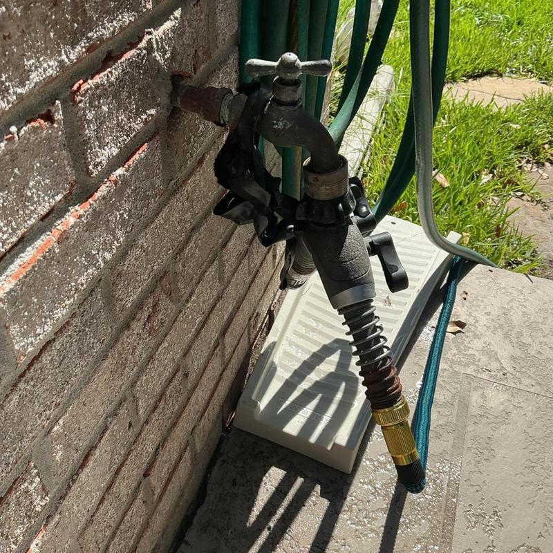 Hose bibb on brick wall with garden hose attached Hose bibb on brick wall with garden hose attached