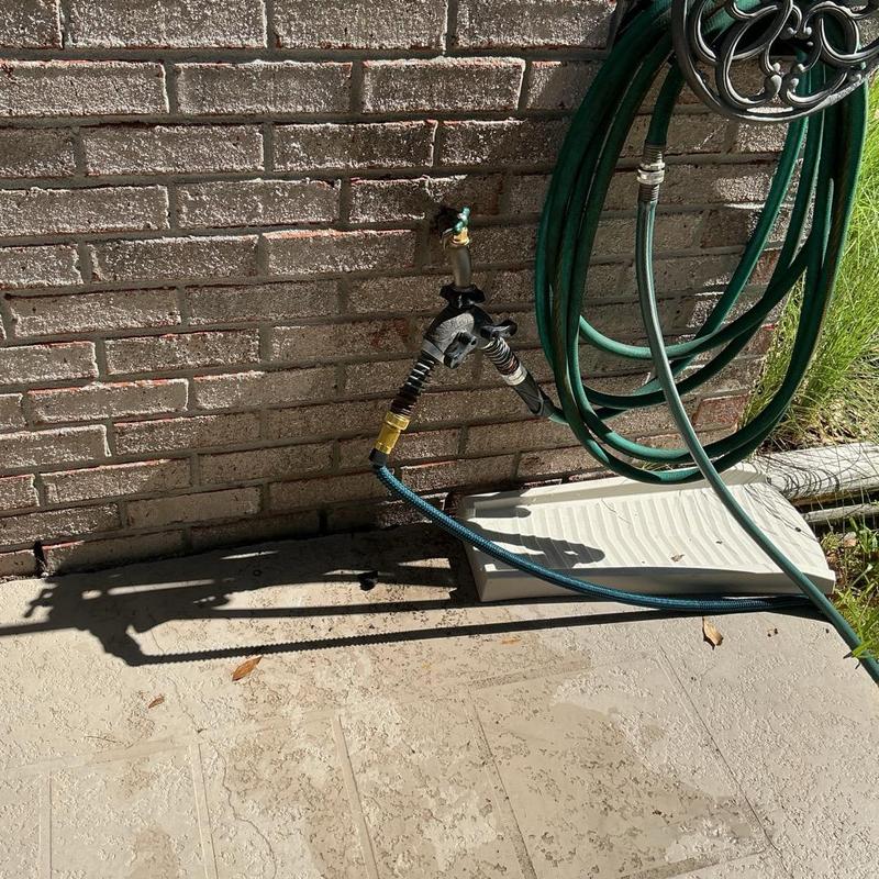 Hose bibb with attached garden hoses on brick wall Hose bibb with attached garden hoses on brick wall