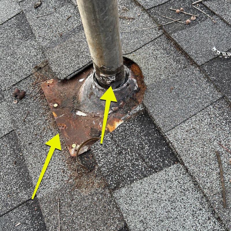 Rusty metal pipe flashing and damaged roof shingles