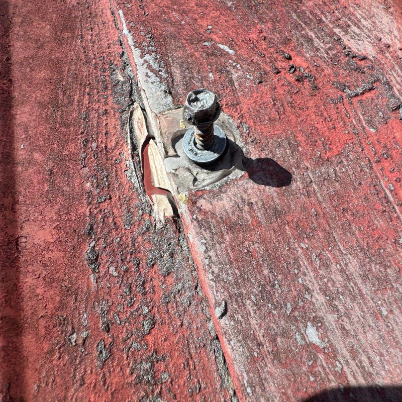 Metal roof panel with damaged screw and sealant failure
