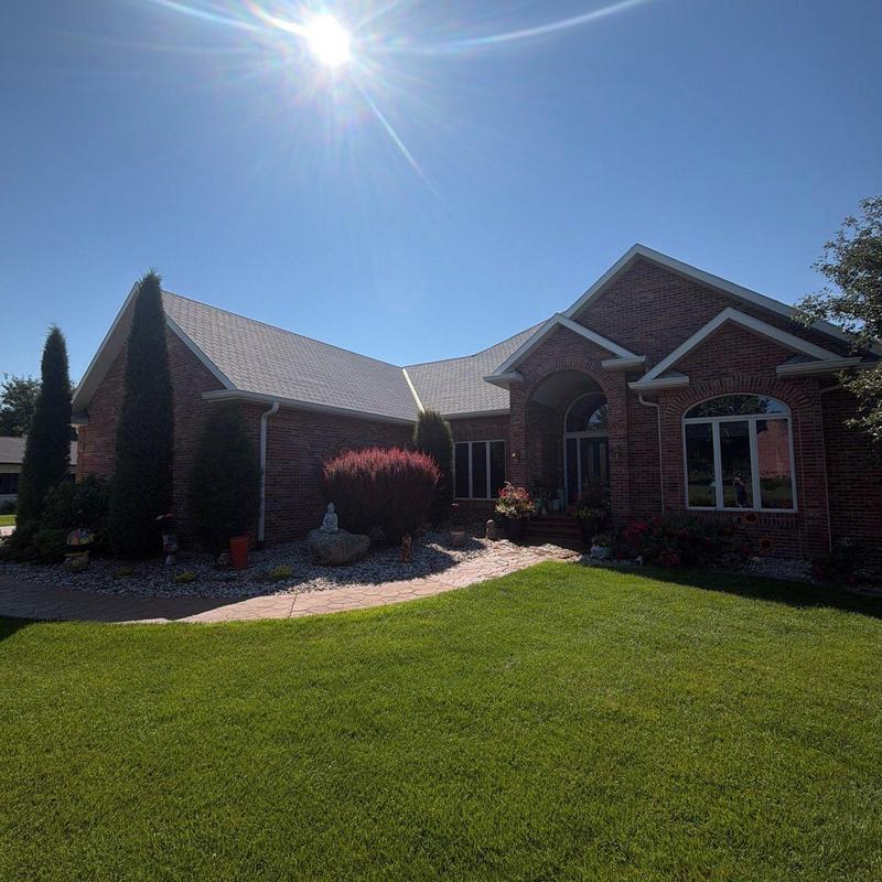 Asphalt shingle roof and brick home exterior in sunlight Asphalt shingle roof and brick home exterior in sunlight