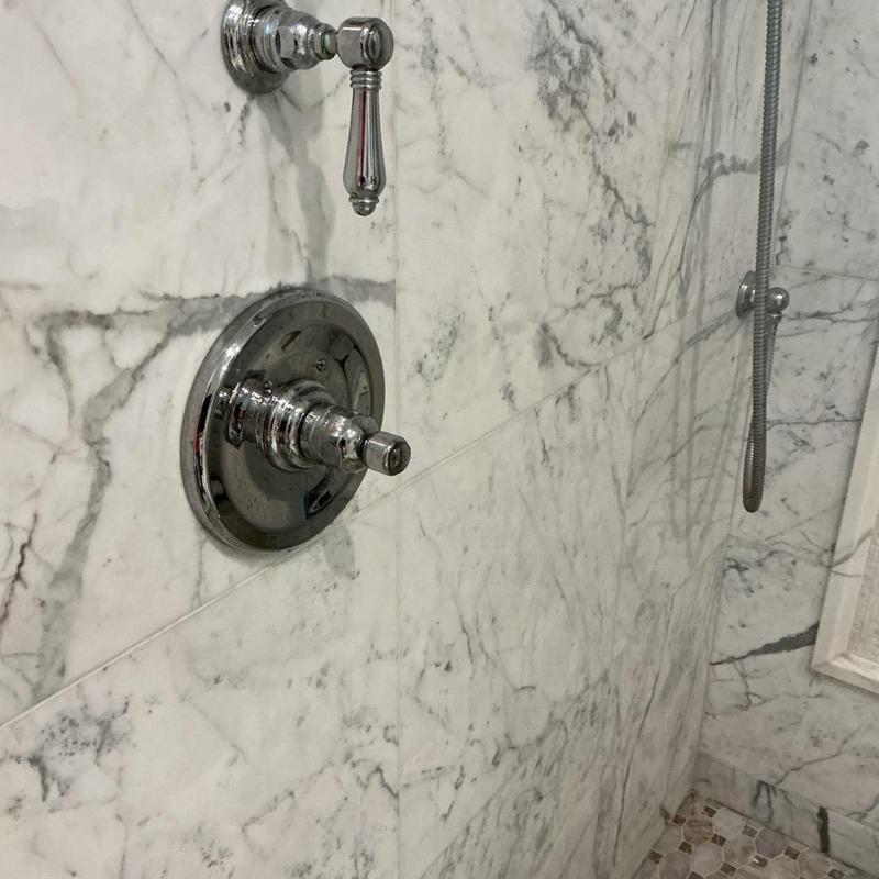 Shower valve and handheld showerhead on marble wall Shower valve and handheld showerhead on marble wall