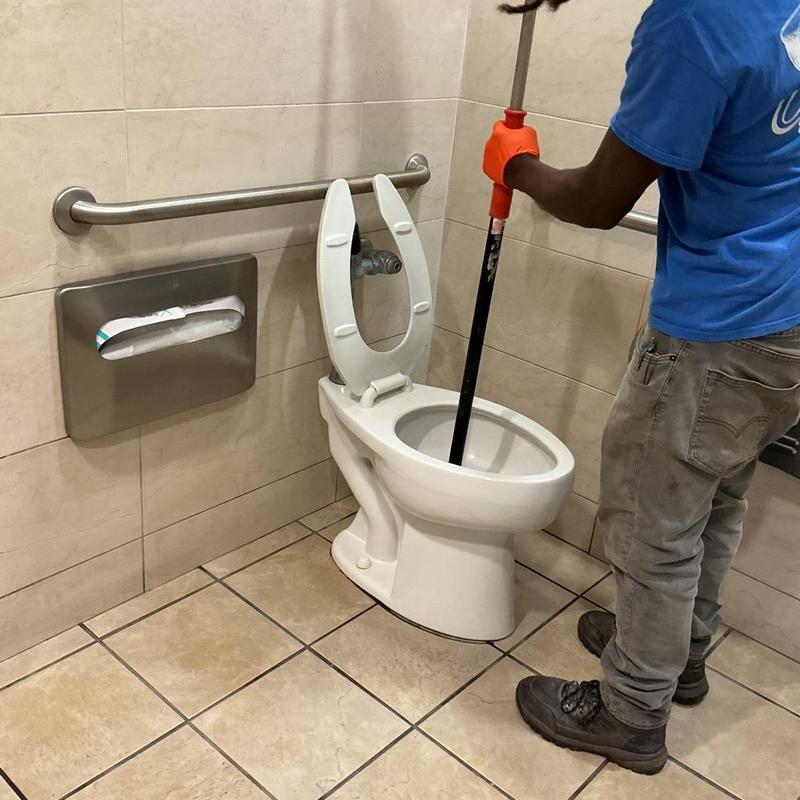 Toilet unclogging in men's restroom with plunger Toilet unclogging in men's restroom with plunger