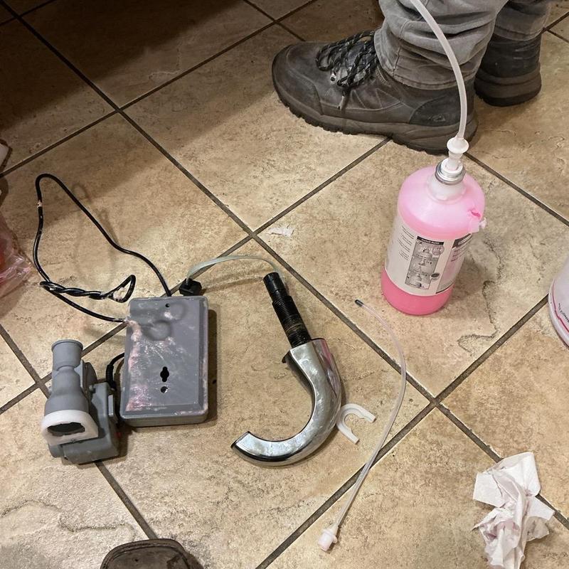 Soap dispenser installation parts and plumber boots on tile Soap dispenser installation parts and plumber boots on tile