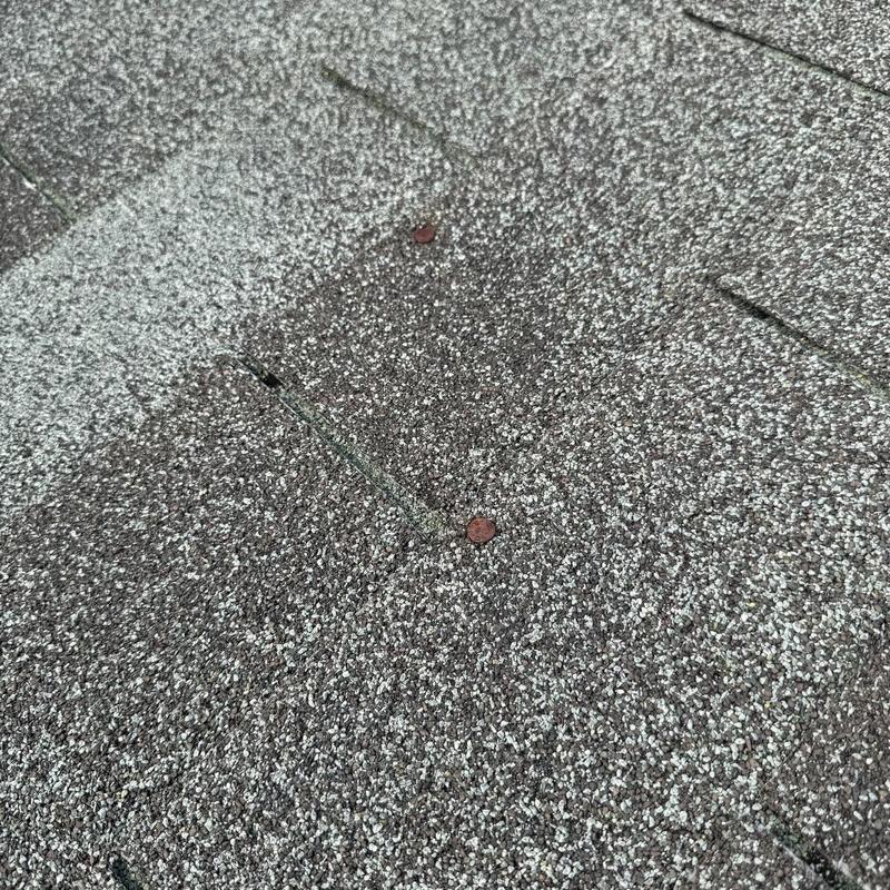 Three-tab asphalt shingles with missing tabs and exposed nails