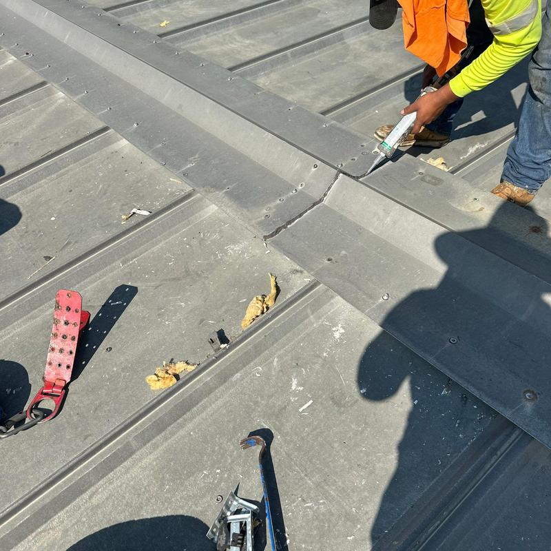 Metal roof flashing sealing with caulking on roof panel joint