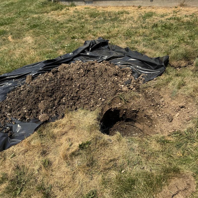 Septic tank excavation with soil pile in yard