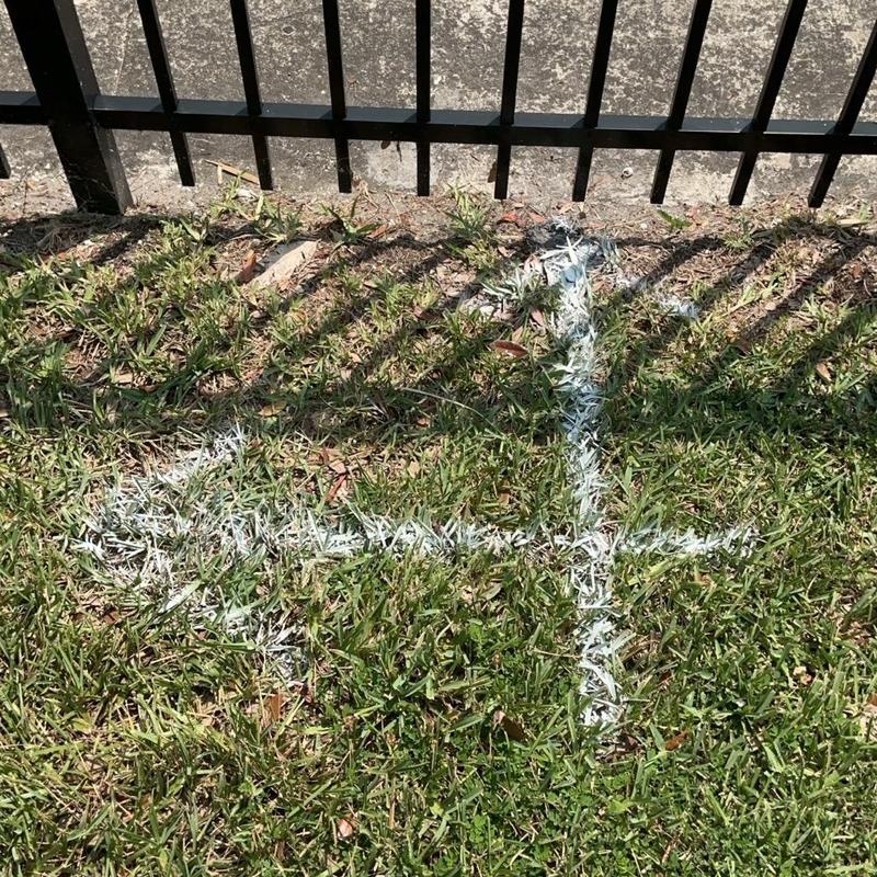 Sewer line direction marked on grass near fence Sewer line direction marked on grass near fence