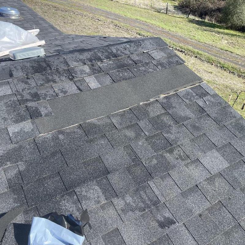 Asphalt shingle roof with new ridge cap installation